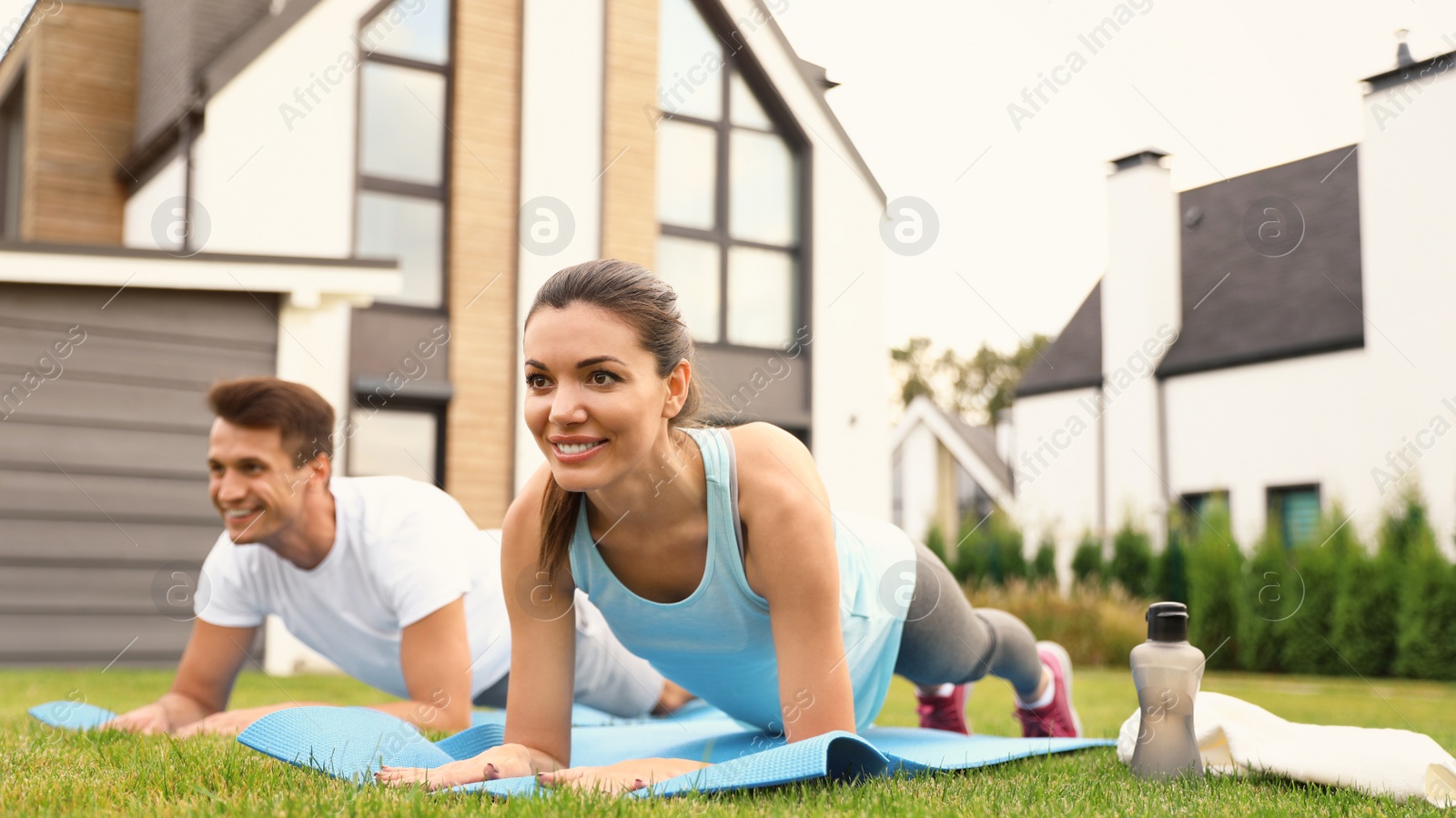 Photo of Sporty couple practicing morning yoga at backyard. Healthy lifestyle