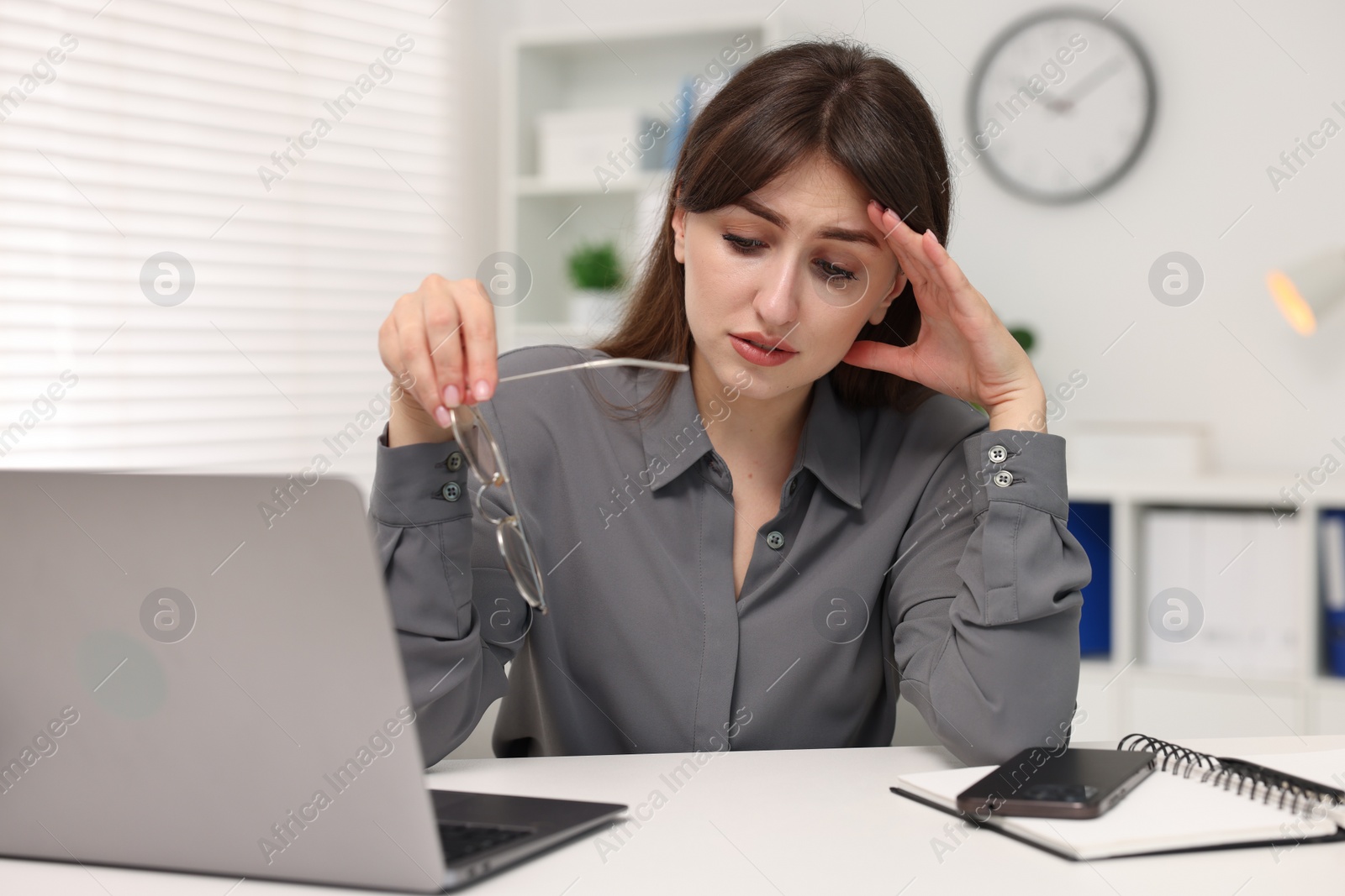 Photo of Overwhelmed woman sitting at table with laptop in office