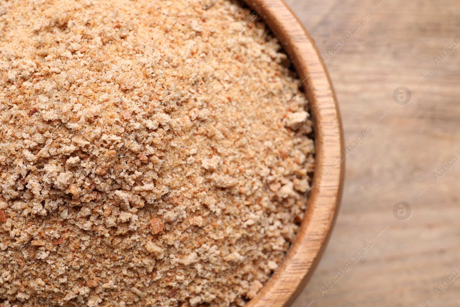 Photo of Fresh breadcrumbs in bowl on wooden table, top view