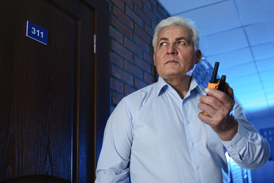 Photo of Professional security guard with portable radio set in dark hallway
