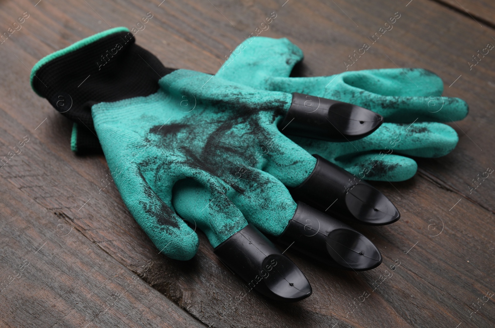 Photo of Pair of claw gardening gloves on wooden table, closeup