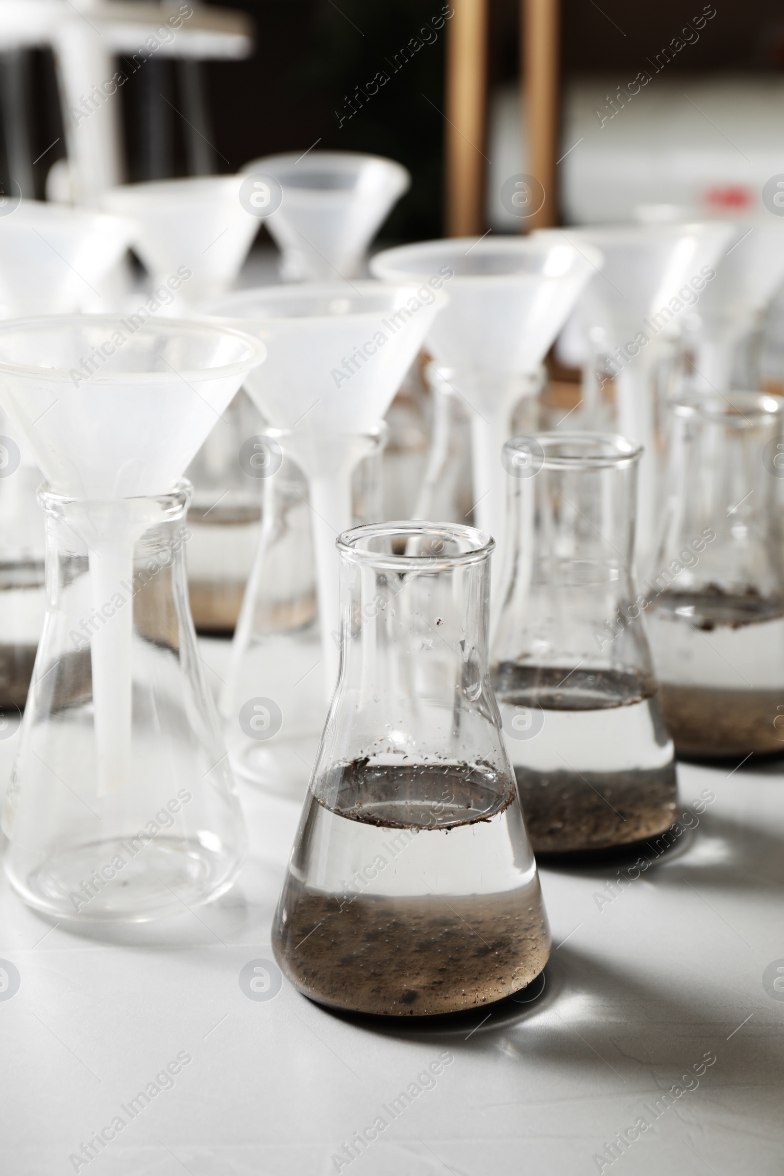 Photo of Laboratory glassware with soil extracts and funnels on table