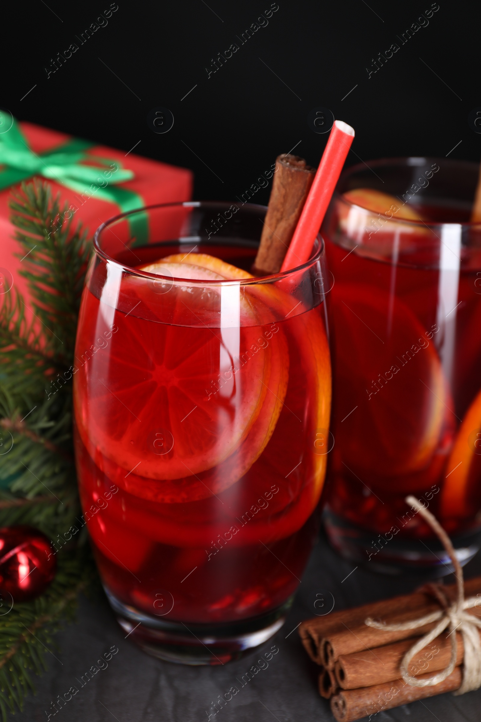 Photo of Delicious Sangria drink in glasses and Christmas decorations on dark table, closeup