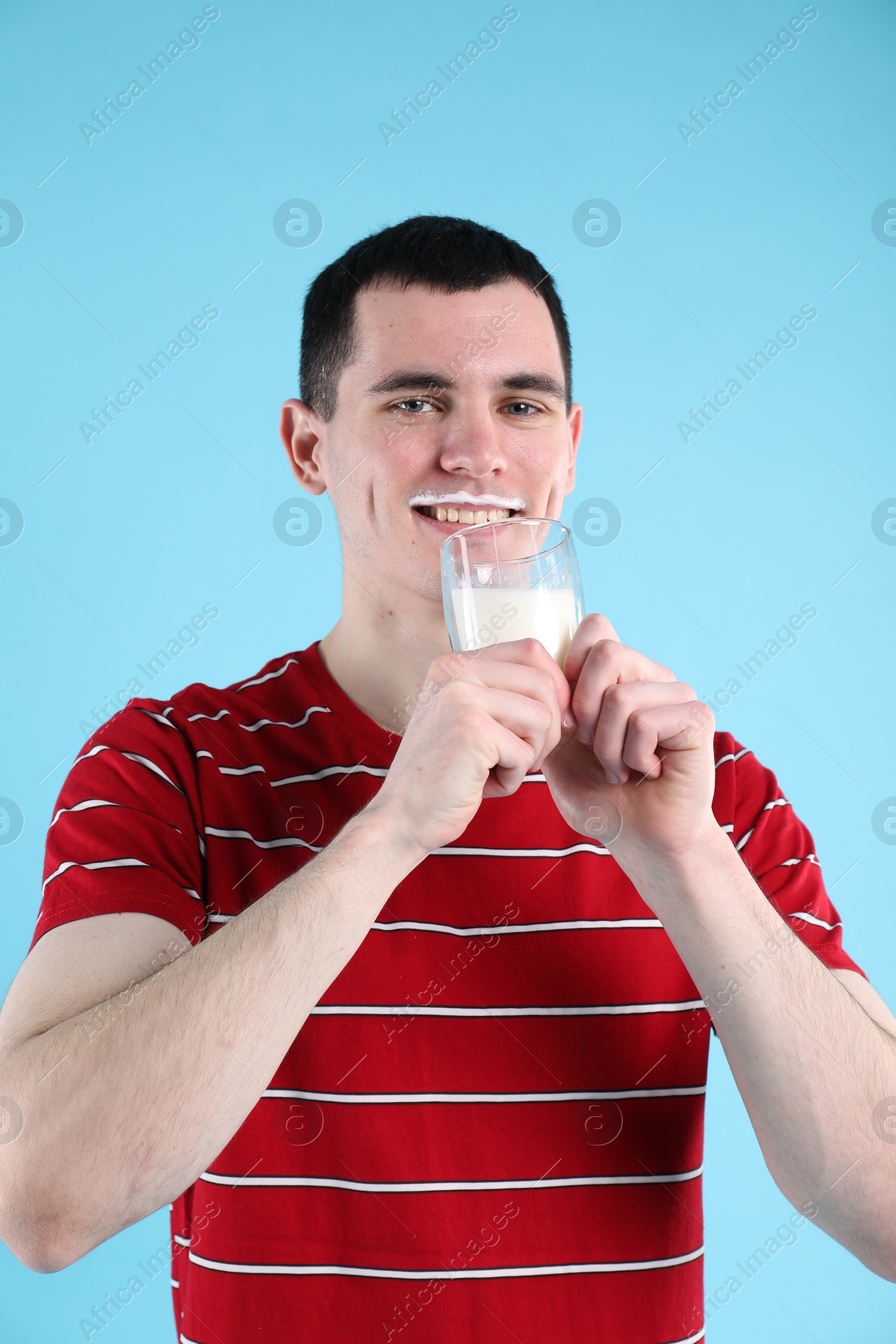 Photo of Milk mustache left after dairy product. Man drinking milk on light blue background