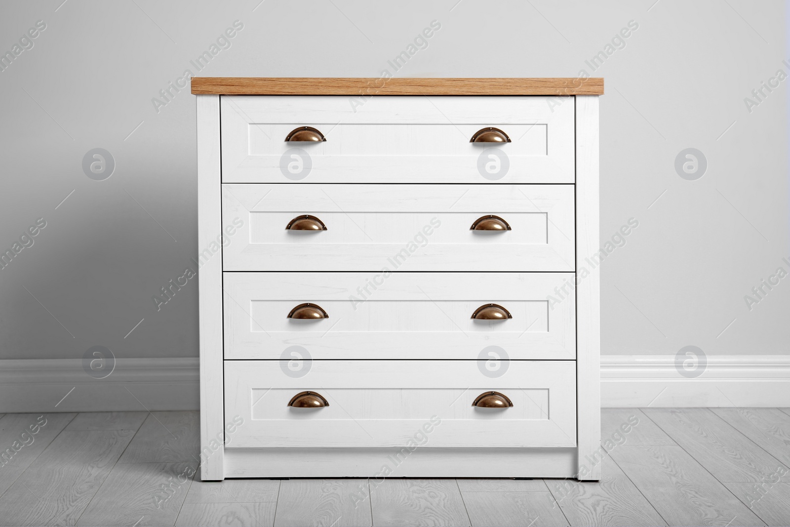 Photo of Stylish chest of drawers near white wall. Furniture for wardrobe room