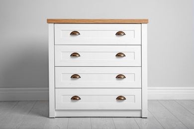 Stylish chest of drawers near white wall. Furniture for wardrobe room