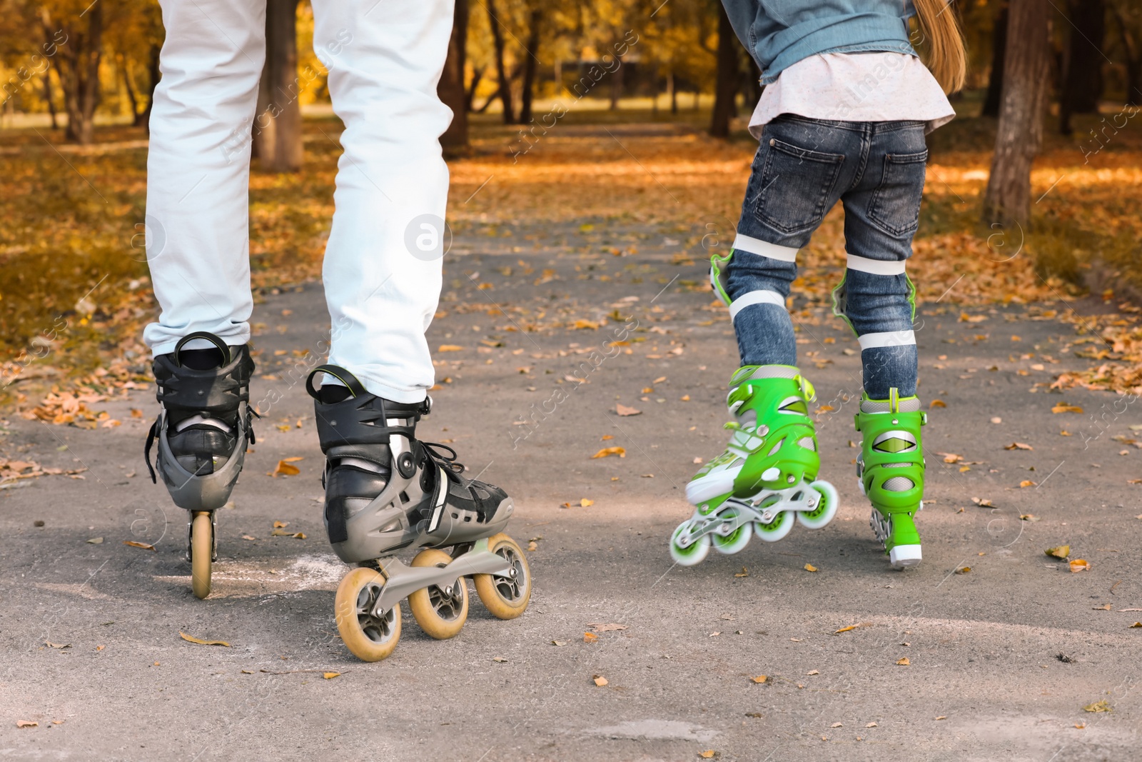 Photo of Father and his daughter roller skating in autumn park