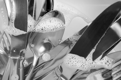 Photo of Washing silver spoons, forks and knives in kitchen sink with water, closeup