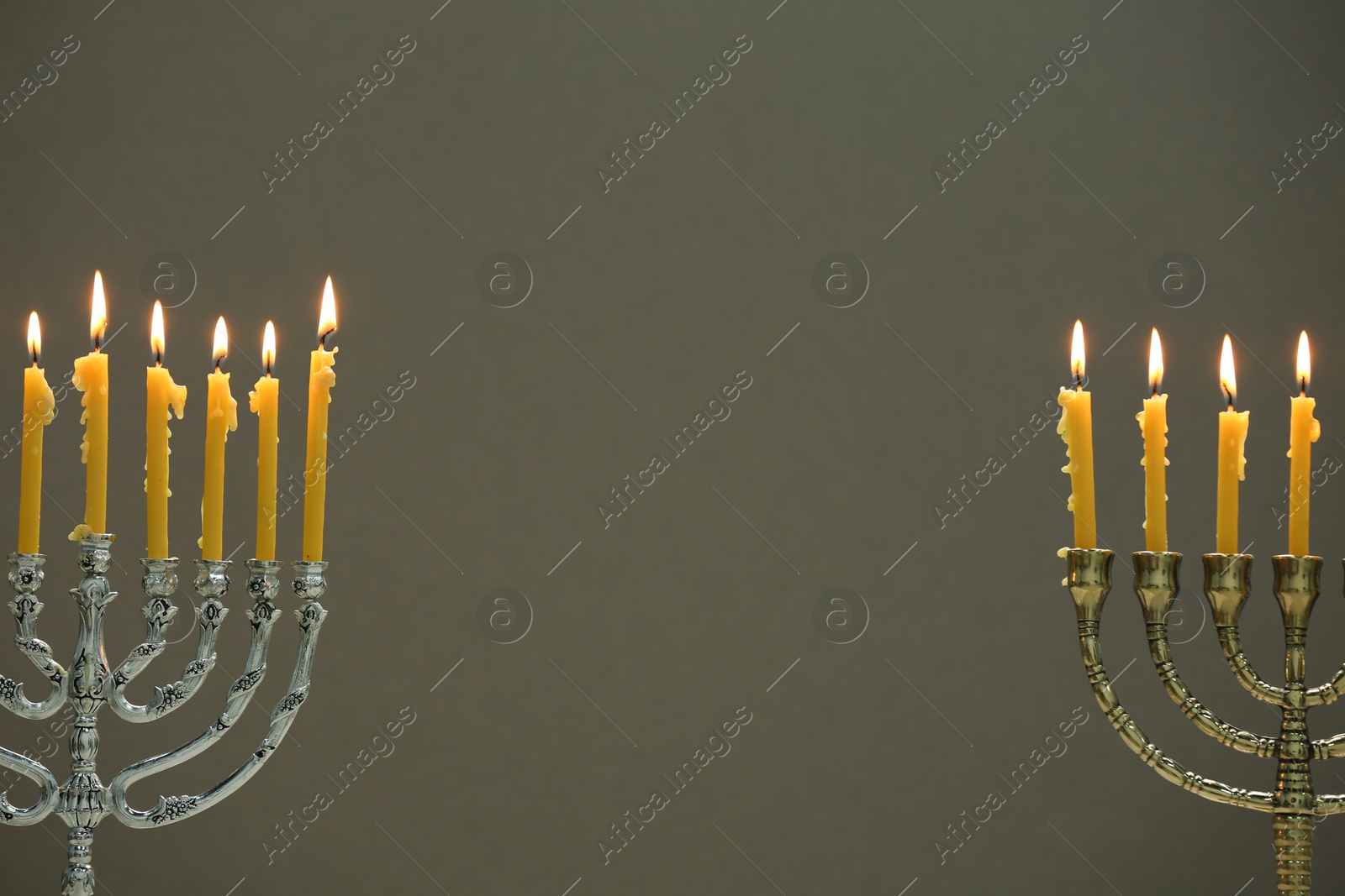 Photo of Hanukkah celebration. Menorahs with burning candles on light background, space for text