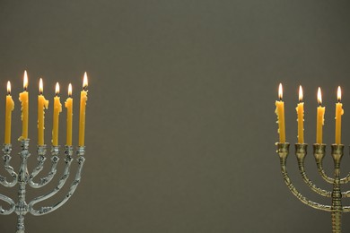 Photo of Hanukkah celebration. Menorahs with burning candles on light background, space for text