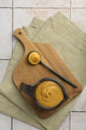 Photo of Tasty mustard sauce on light tiled table, top view