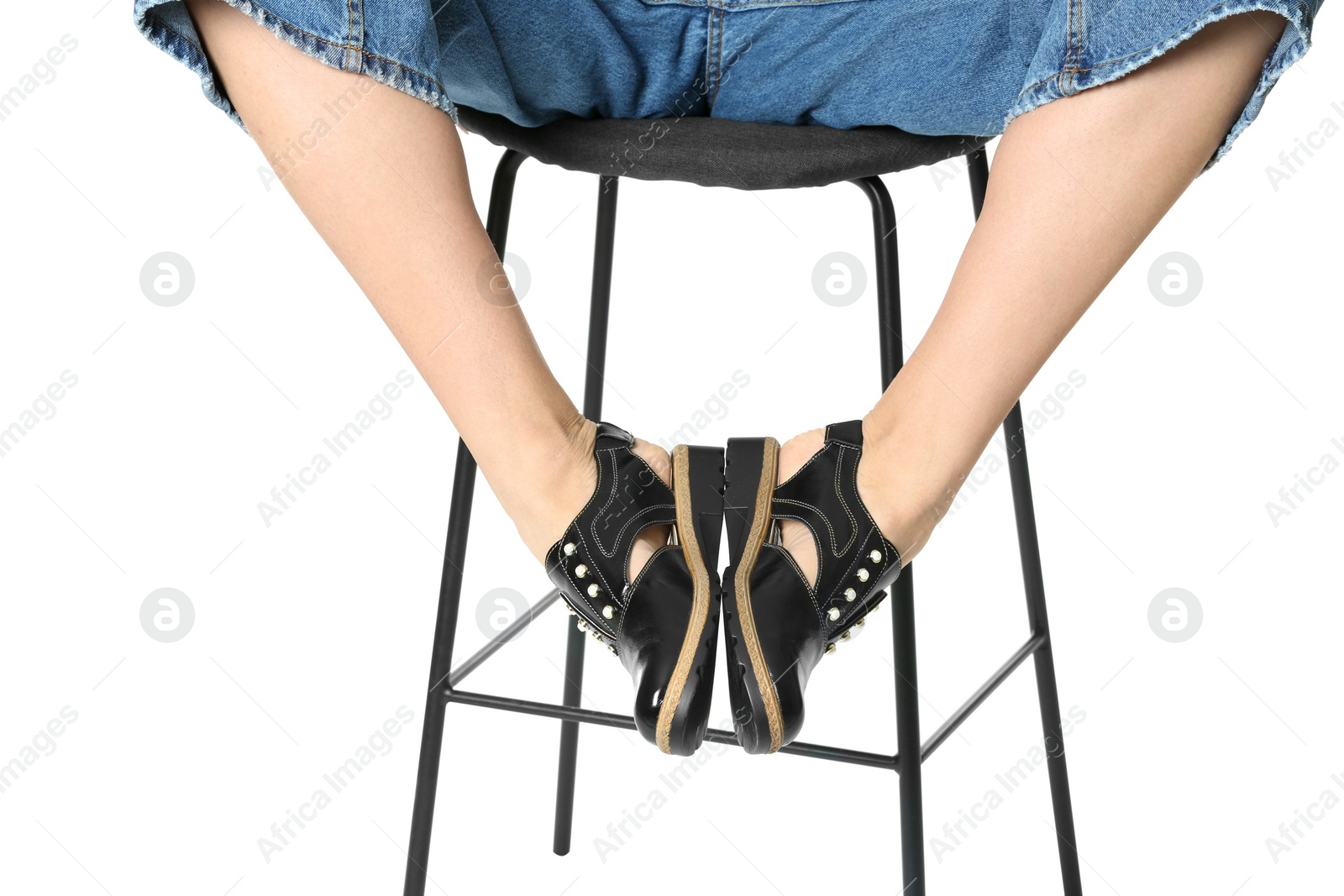 Photo of Woman in stylish shoes on stool against white background, closeup