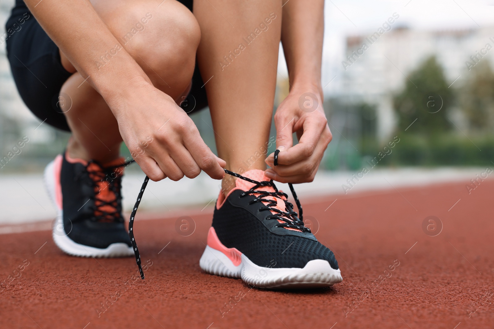 Photo of Woman tying shoelaces before training outdoors. closeup. Space for text