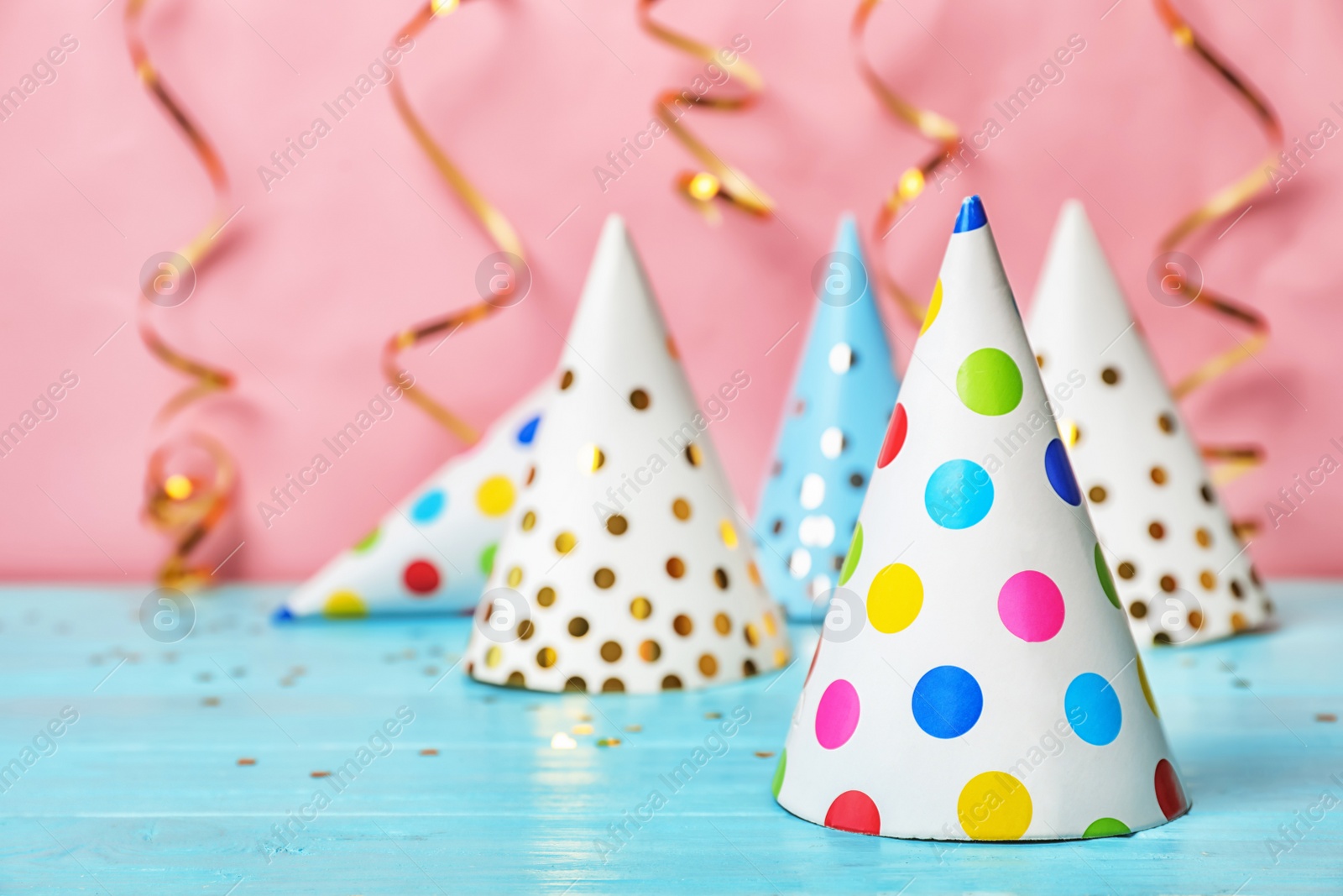 Photo of Birthday party caps on table against color background