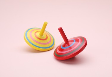 Photo of Two bright spinning tops on beige background. Toy whirligig