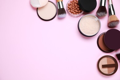 Different face powders and makeup brushes on pink background, flat lay. Space for text