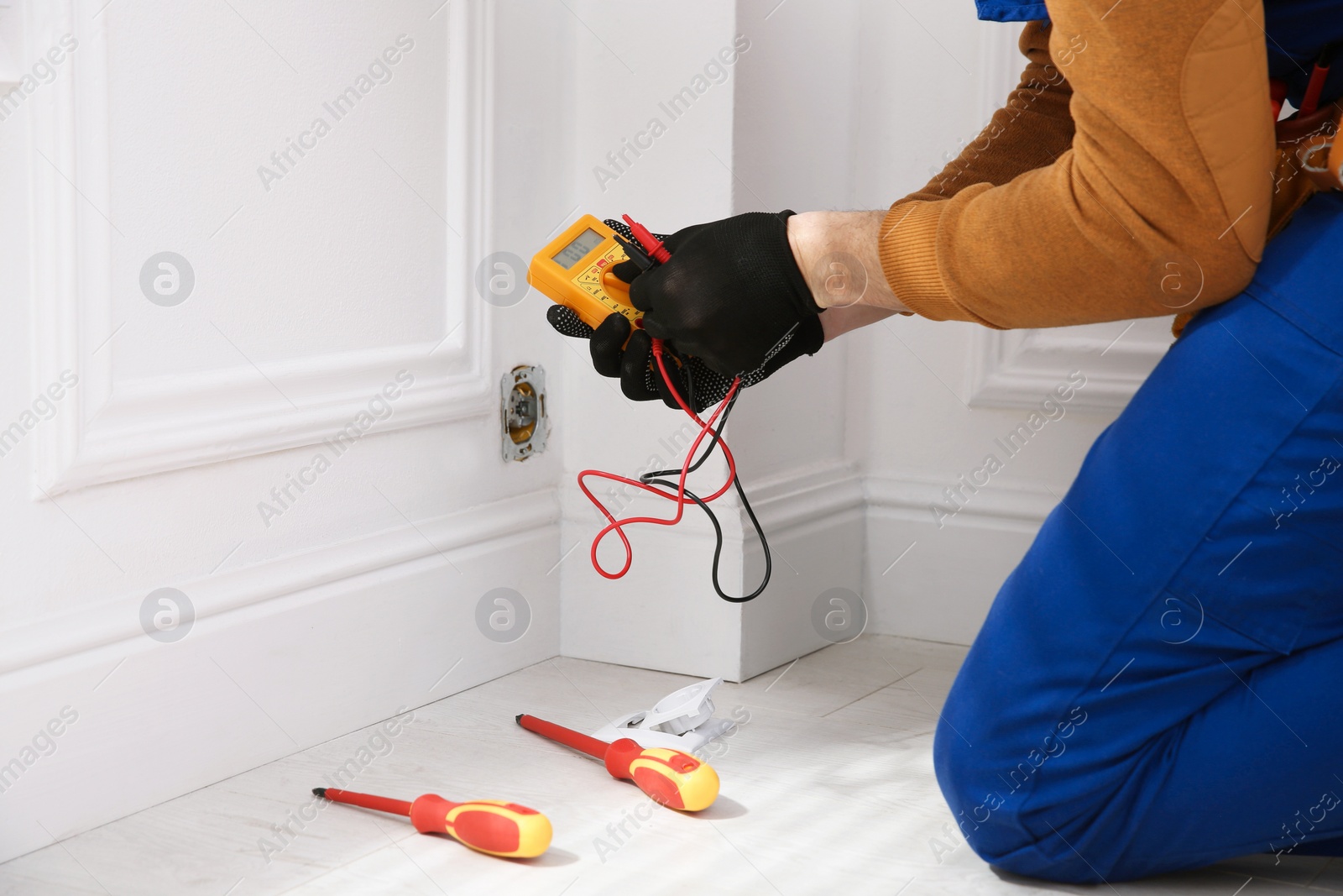 Photo of Electrician with tester checking voltage indoors, closeup