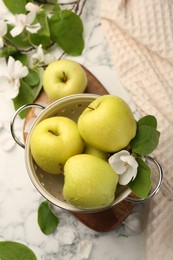 Photo of Colander with fresh apples and beautiful spring blossoms on white marble table, flat lay