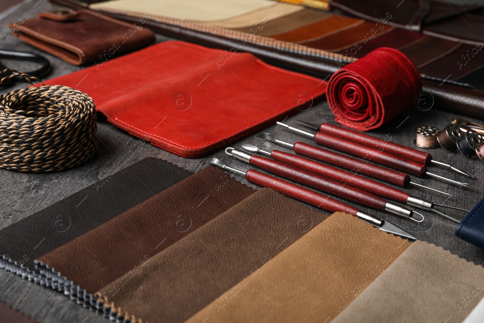 Photo of Leather samples and craftsman tools on grey stone background