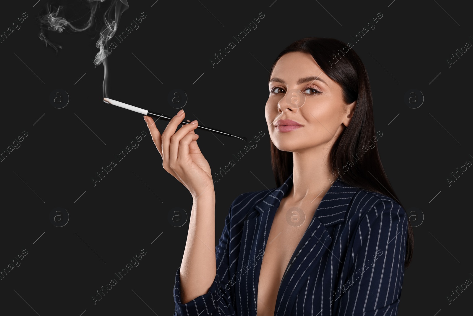 Photo of Woman using long cigarette holder for smoking on black background