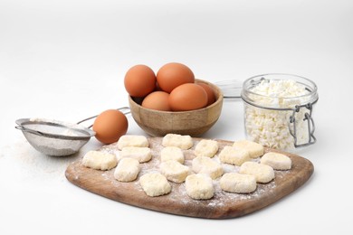 Photo of Making lazy dumplings. Wooden board with cut dough and ingredients isolated on white