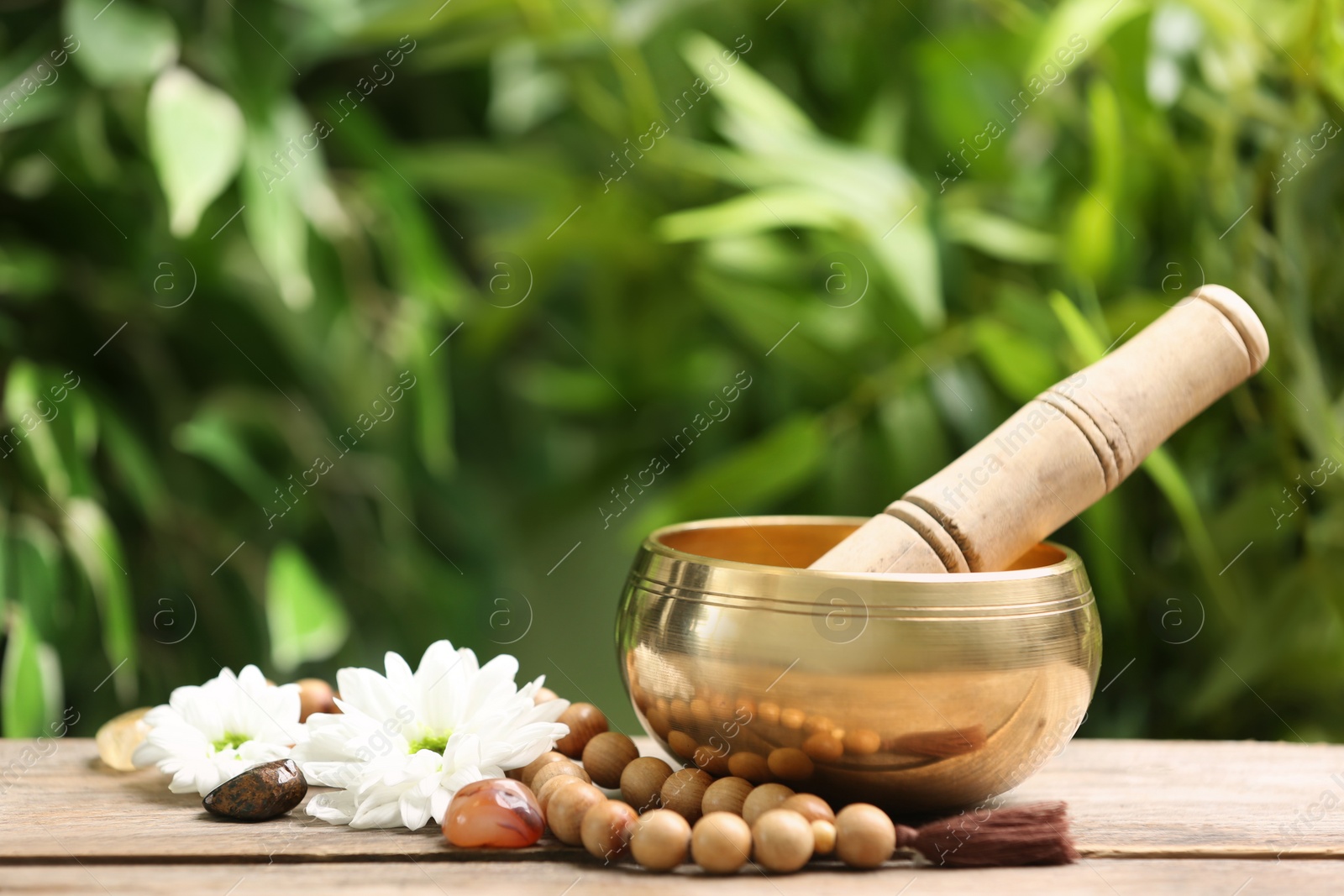 Photo of Composition with tibetan singing bowl and different gemstones on wooden table outdoors, space for text. Sound healing