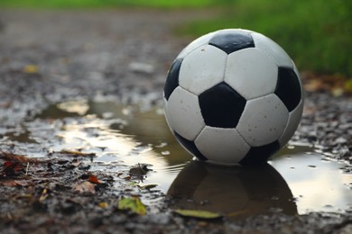 Photo of Leather soccer ball in puddle outdoors, space for text