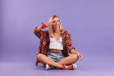 Photo of Happy hippie woman showing peace sign on purple background