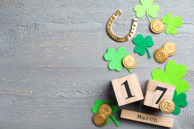 Flat lay composition with horseshoe and block calendar on grey wooden background, space for text. St. Patrick's Day celebration