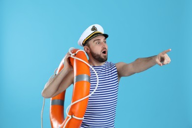Surprised sailor with ring buoy on light blue background