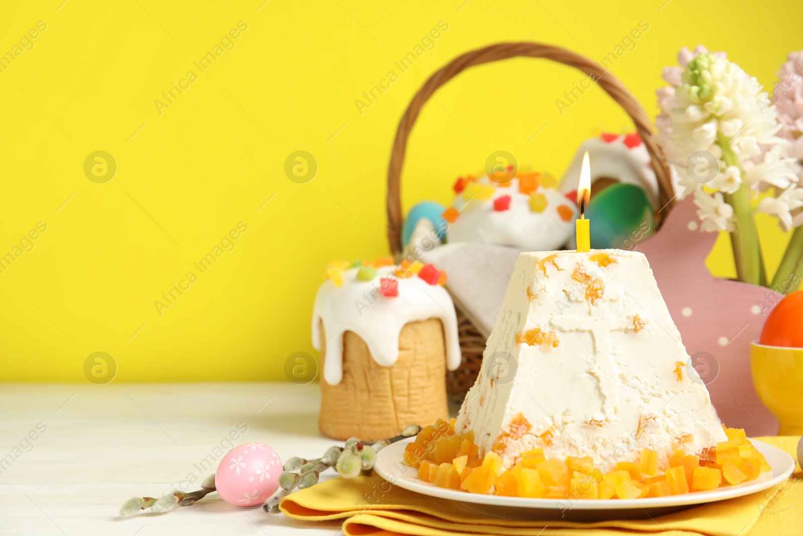 Photo of Traditional cottage cheese Easter paskha with dried apricot and burning candle on white wooden table, space for text