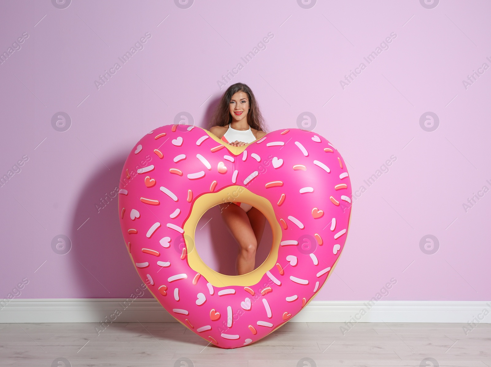 Photo of Beautiful young woman with inflatable heart near color wall