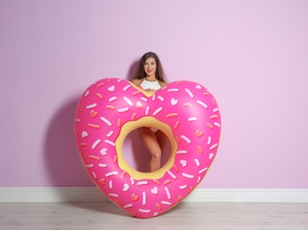 Beautiful young woman with inflatable heart near color wall