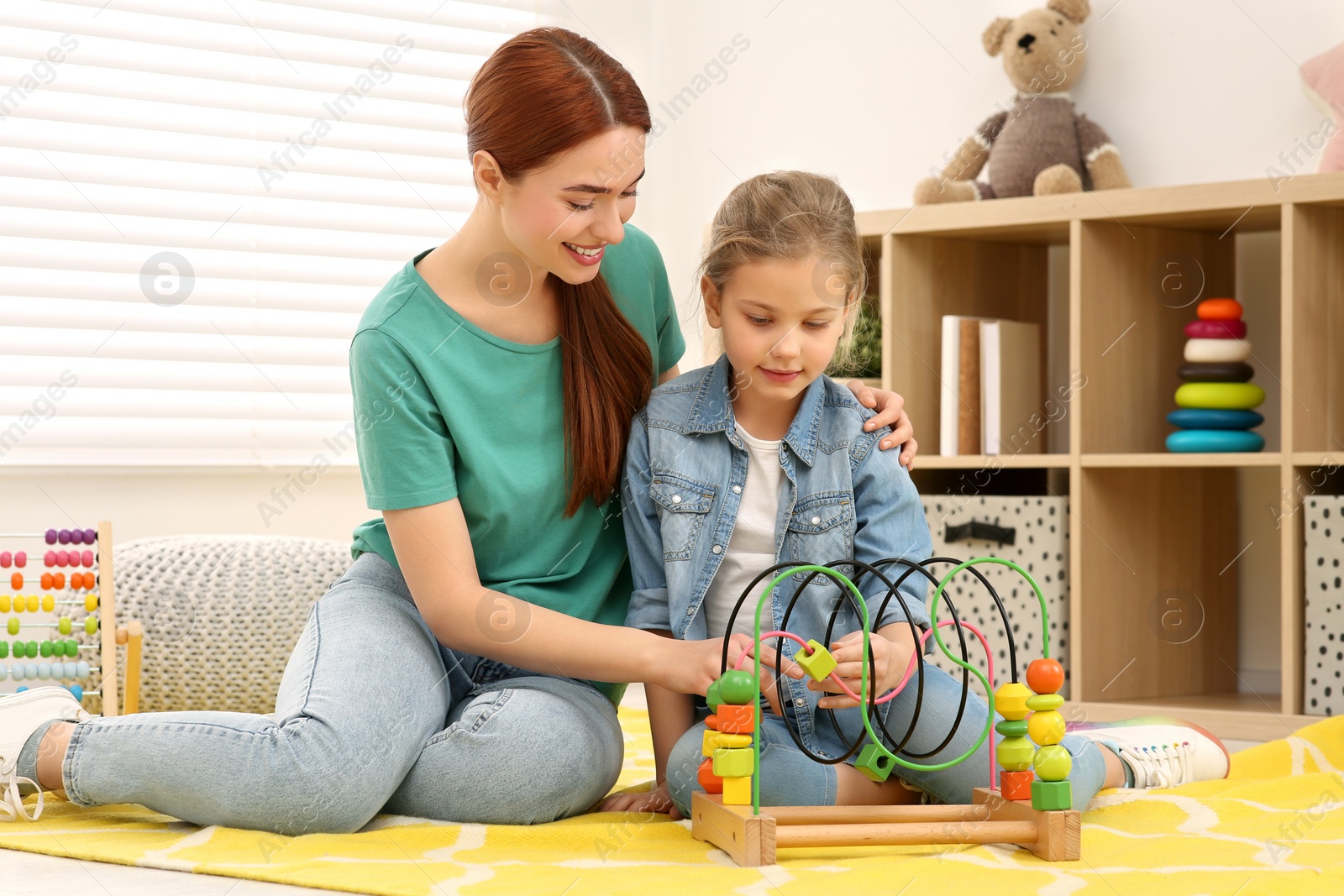 Photo of Happy mother and daughter playing with bead maze on floor in room. Learning mathematics with fun