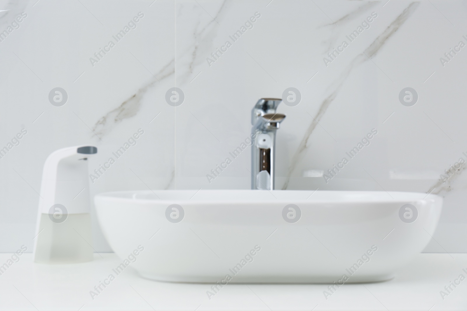 Photo of Modern automatic soap dispenser near sink in bathroom