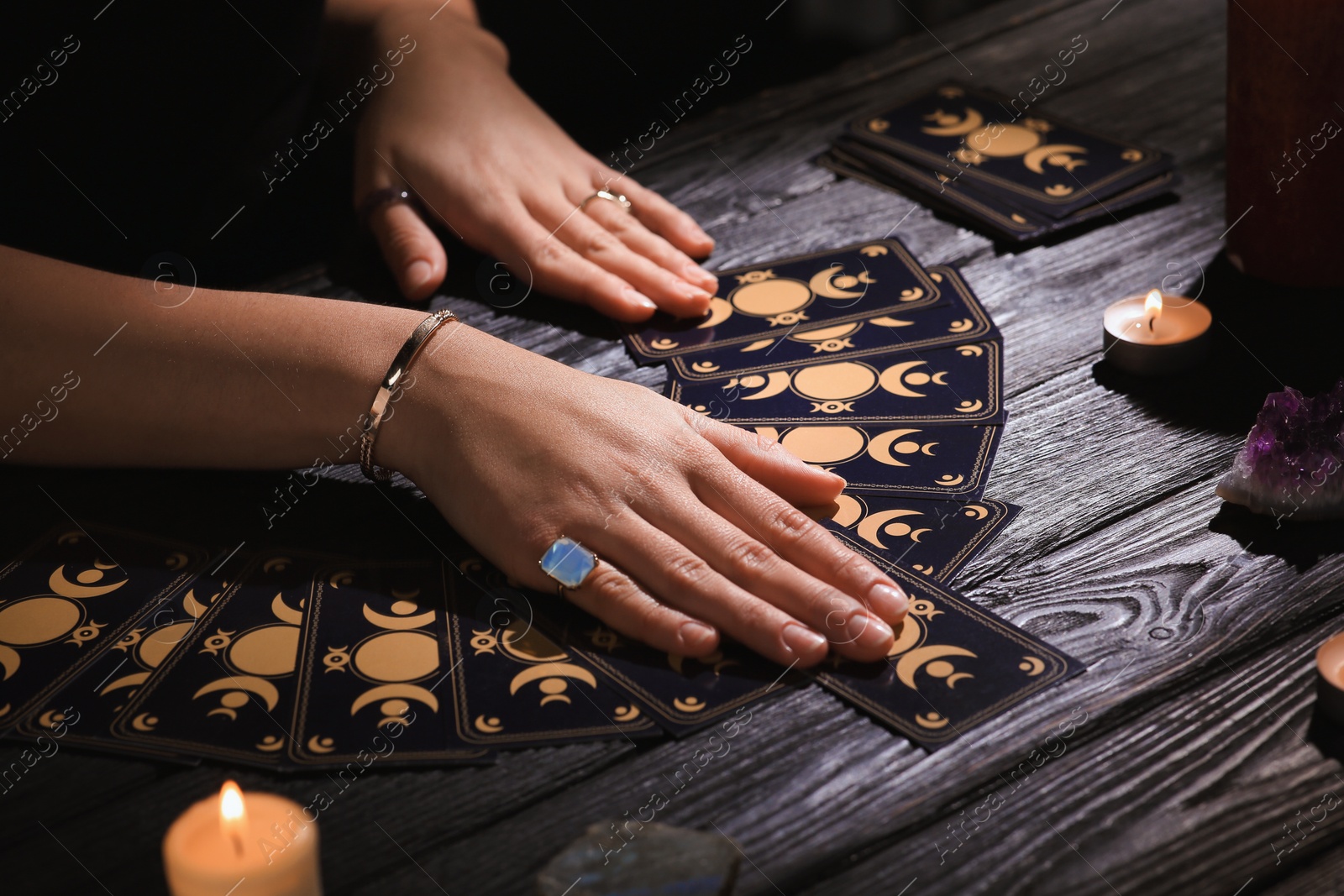 Photo of Soothsayer predicting future with tarot cards at table in darkness, closeup