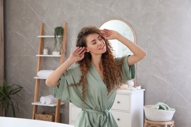 Photo of Beautiful woman wearing green silk robe in bathroom
