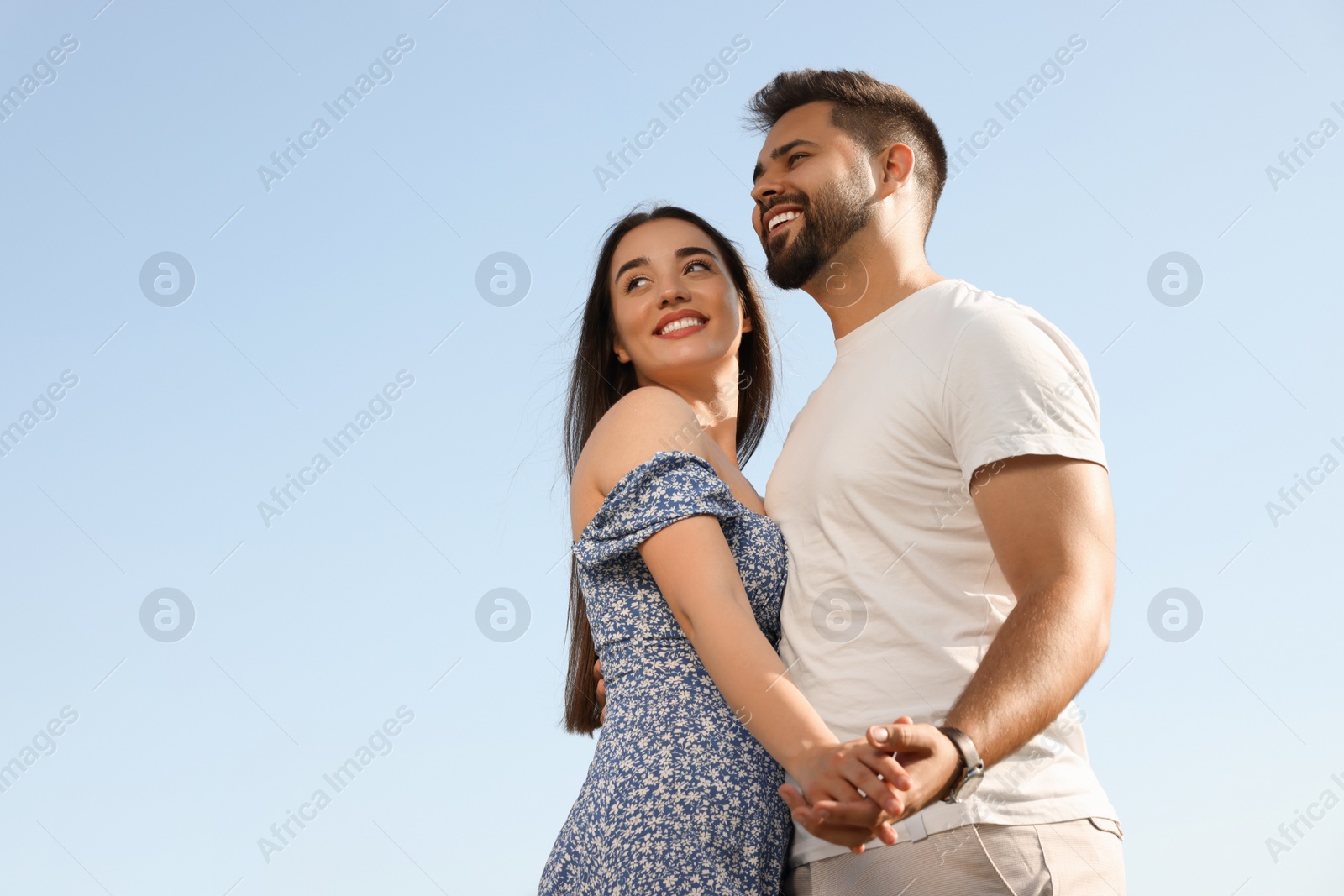 Photo of Romantic date. Beautiful couple spending time together against blue sky, low angle view with space for text