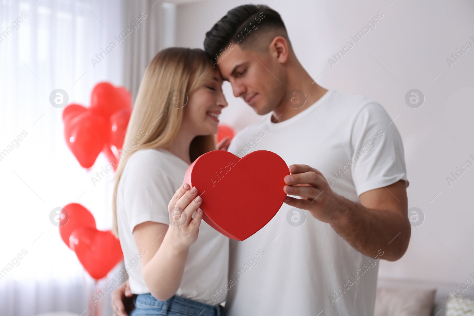 Photo of Lovely couple with gift in room. Valentine's day celebration