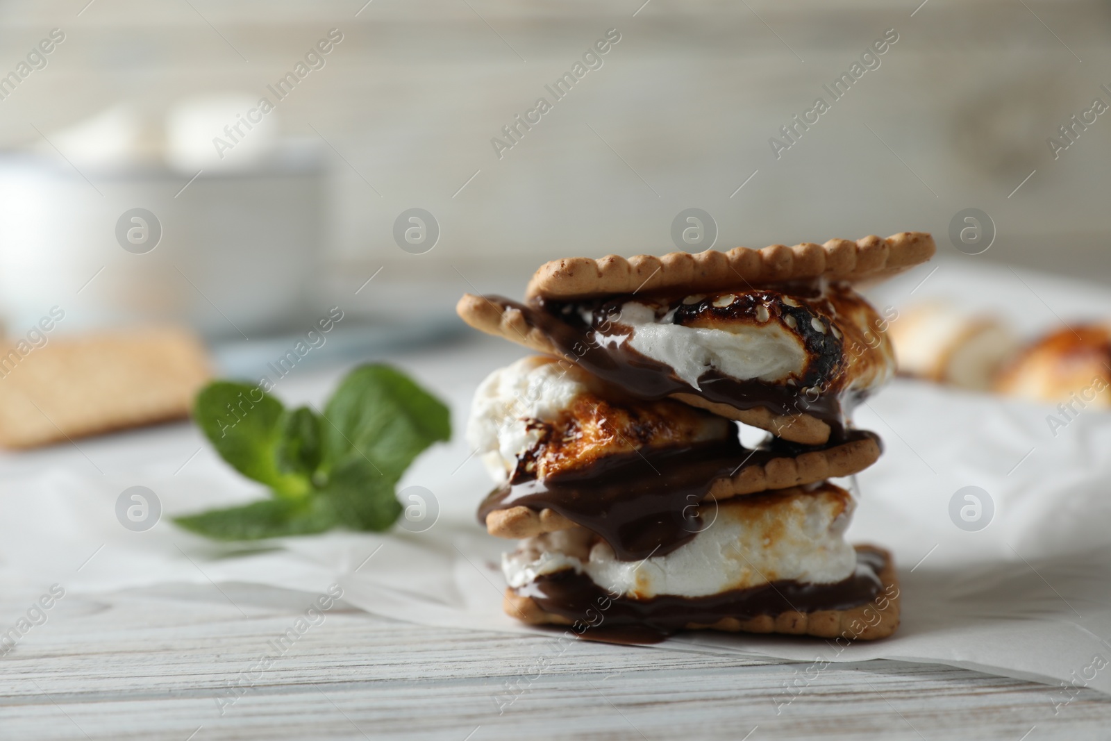 Photo of Delicious marshmallow sandwich with cracker and chocolate on white wooden table, closeup. Space for text