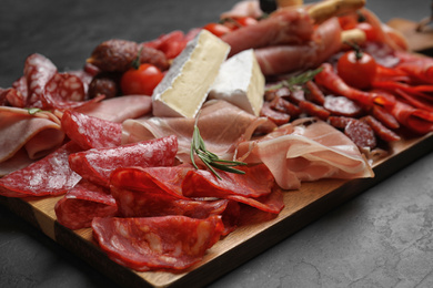 Tasty ham with other delicacies served on black table, closeup