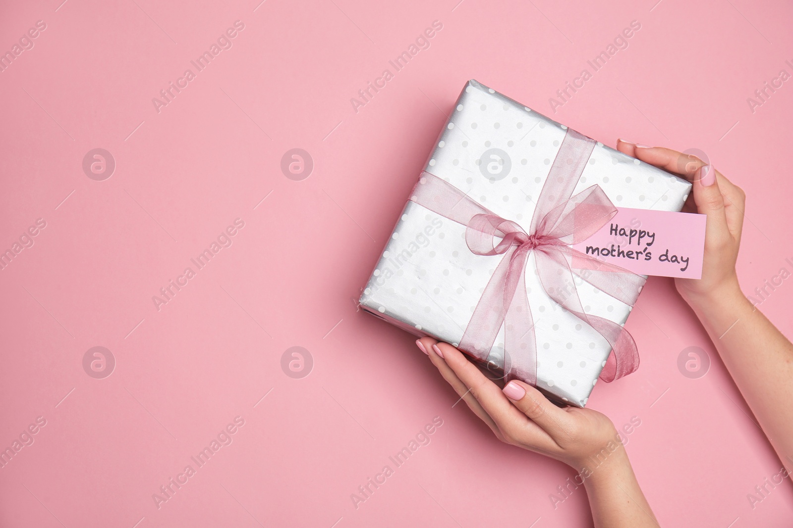 Photo of Woman holding elegant gift box for Mother's Day on color background, top view