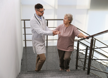 Doctor helping senior patient in modern hospital