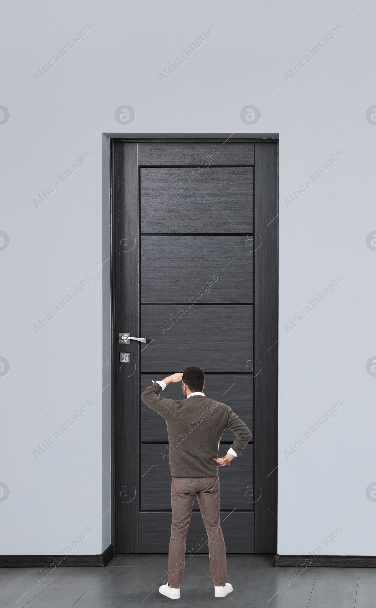 Image of Man standing in front of door, back view