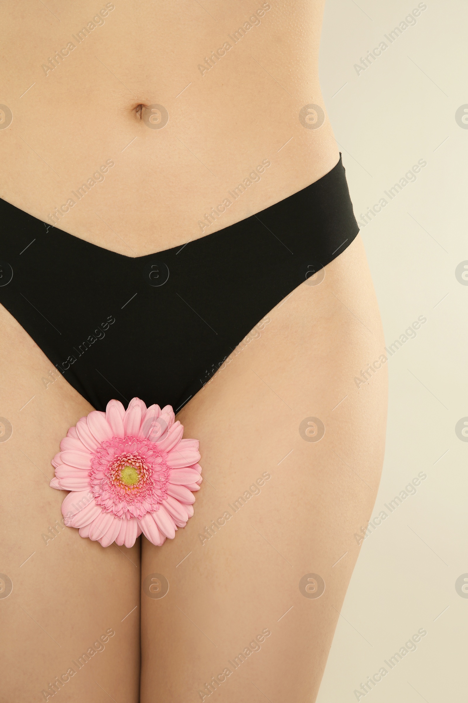 Photo of Gynecology. Woman in underwear with gerbera flower on light background, closeup