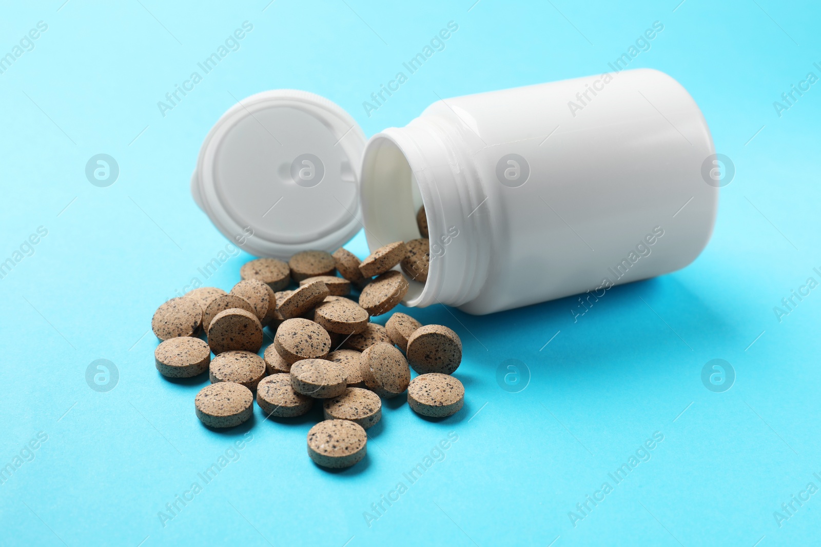 Photo of Bottle and vitamin pills on light blue background