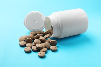 Photo of Bottle and vitamin pills on light blue background