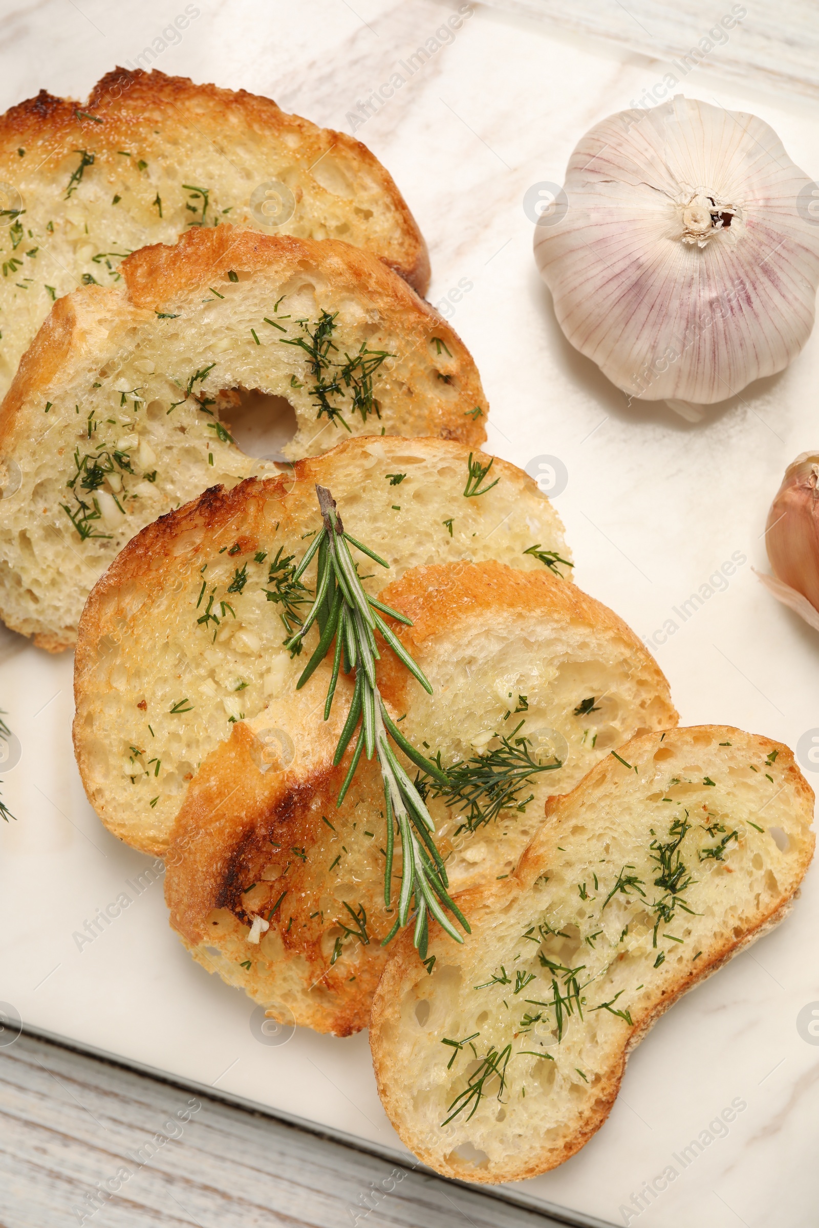 Photo of Tasty baguette with garlic, dill and rosemary on white wooden table, top view