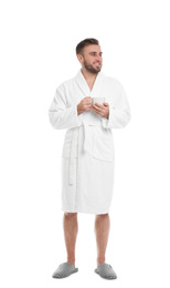 Handsome man in bathrobe with cup of coffee on white background