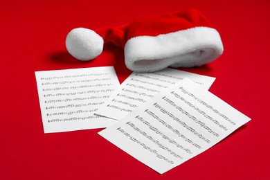 Photo of Note sheets and Santa hat on red background